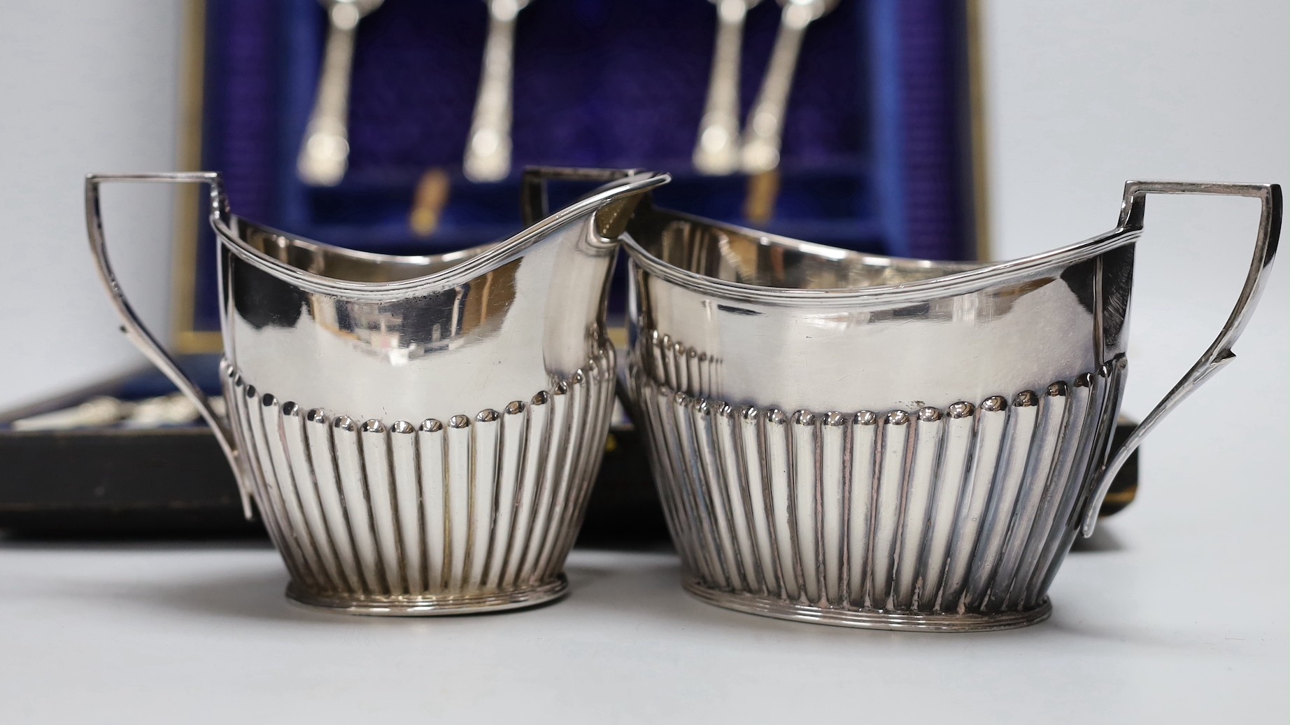 Six pairs of silver plated and engraved dessert knives and forks, with server, mother of pearl handles and six teaspoons (cased) and a silver plated cream jug and sugar bowl.